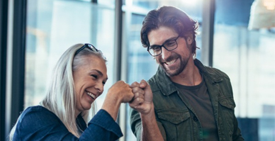 A young man and older woman smiling while bumping fists