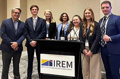 seven IREM members standing around a podium